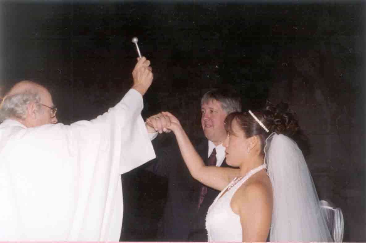 Amy y Jeff recibiendo la bendici�n matrimonial del Rev. Padre Miguel Garnett.
